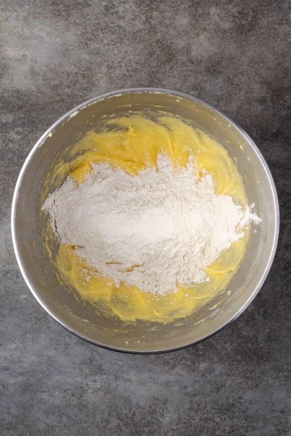 Flour added to the wet ingredients in a mixing bowl.