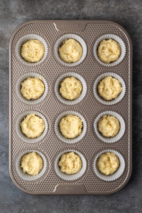 Cinnamon muffin batter in a lined 12-well muffin pan.