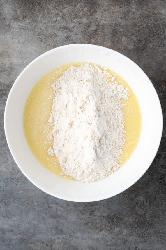 Dry ingredients added to muffin batter in a large white bowl.