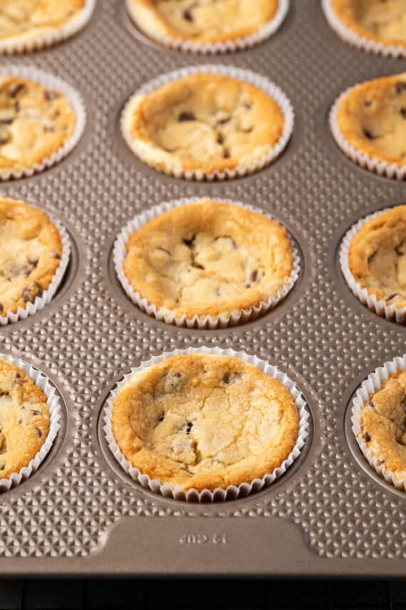 Baked cookie cups inside a muffin tin.