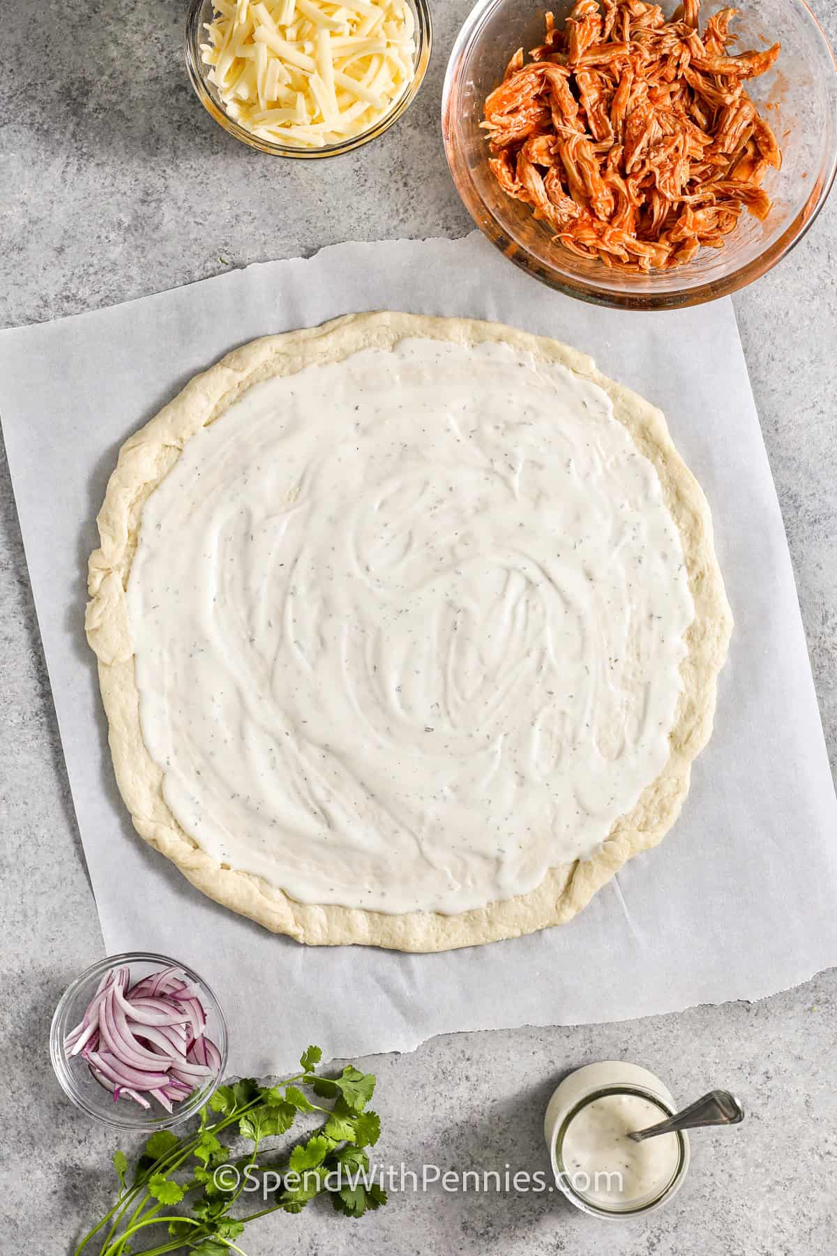 Blue cheese spread on dough to make Buffalo chicken pizza