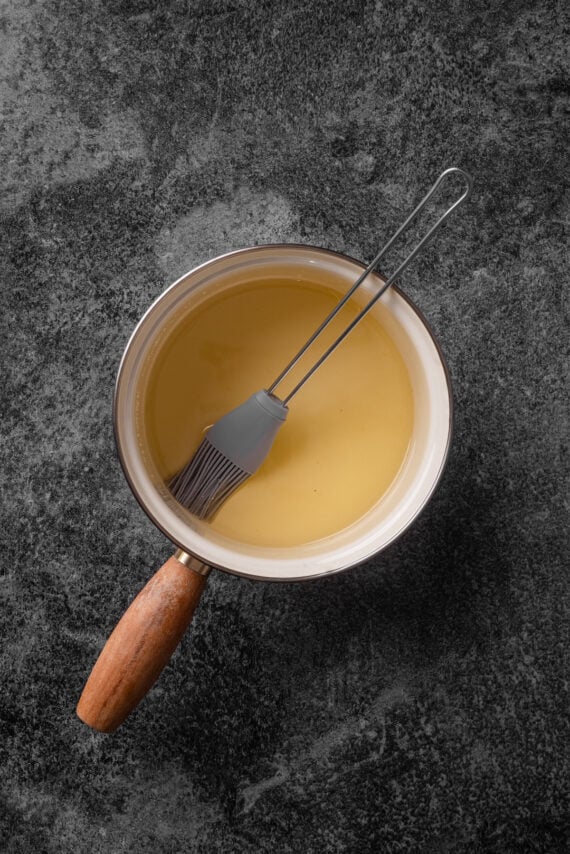 Honey water in a saucepan with a rubber basting brush.