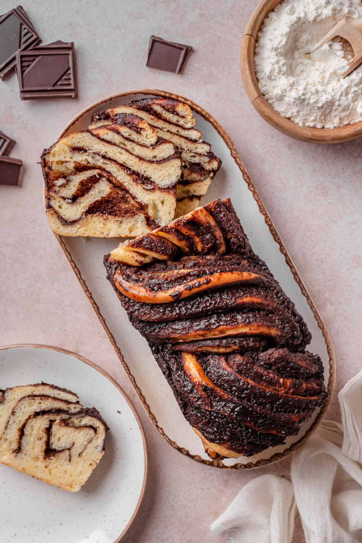 Overhead view of a chocolate babka on a long plate with slicse missing from the end.