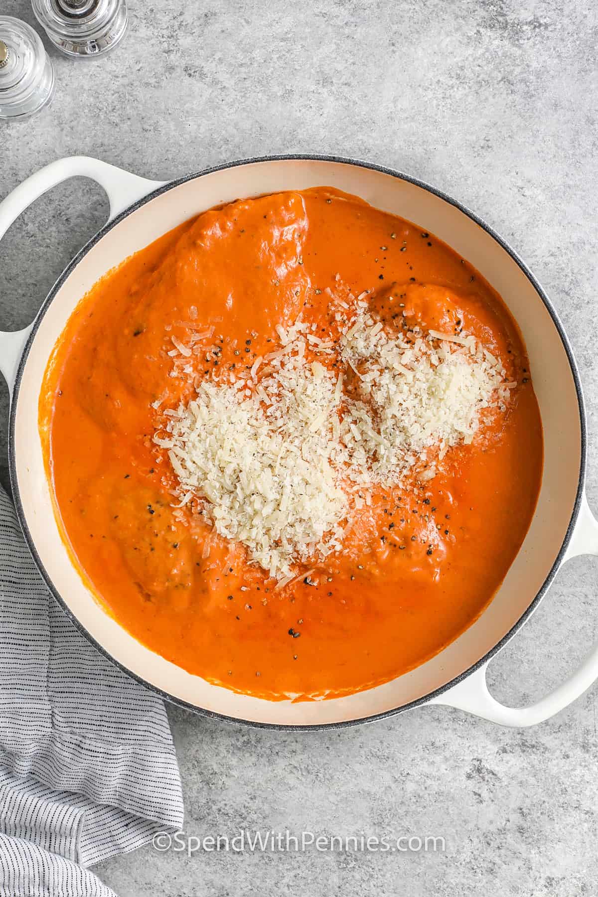 adding chicken and parmesan to pot to make Creamy Tomato Chicken Skillet