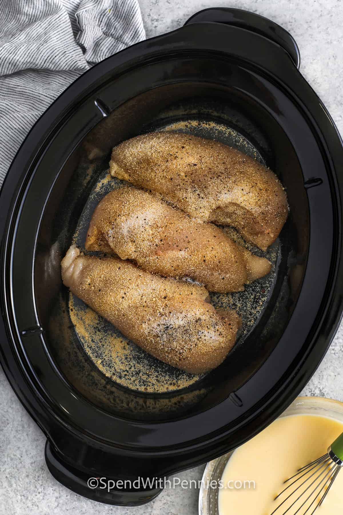 adding chicken with seasoning to crockpot to make Crockpot Chicken and Stuffing