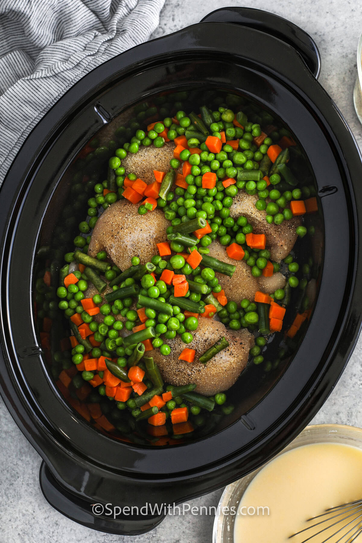 adding mixed vegetables to crockpot to make Crockpot Chicken and Stuffing