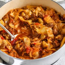 ground beef and cabbage in a dutch oven with a spoon