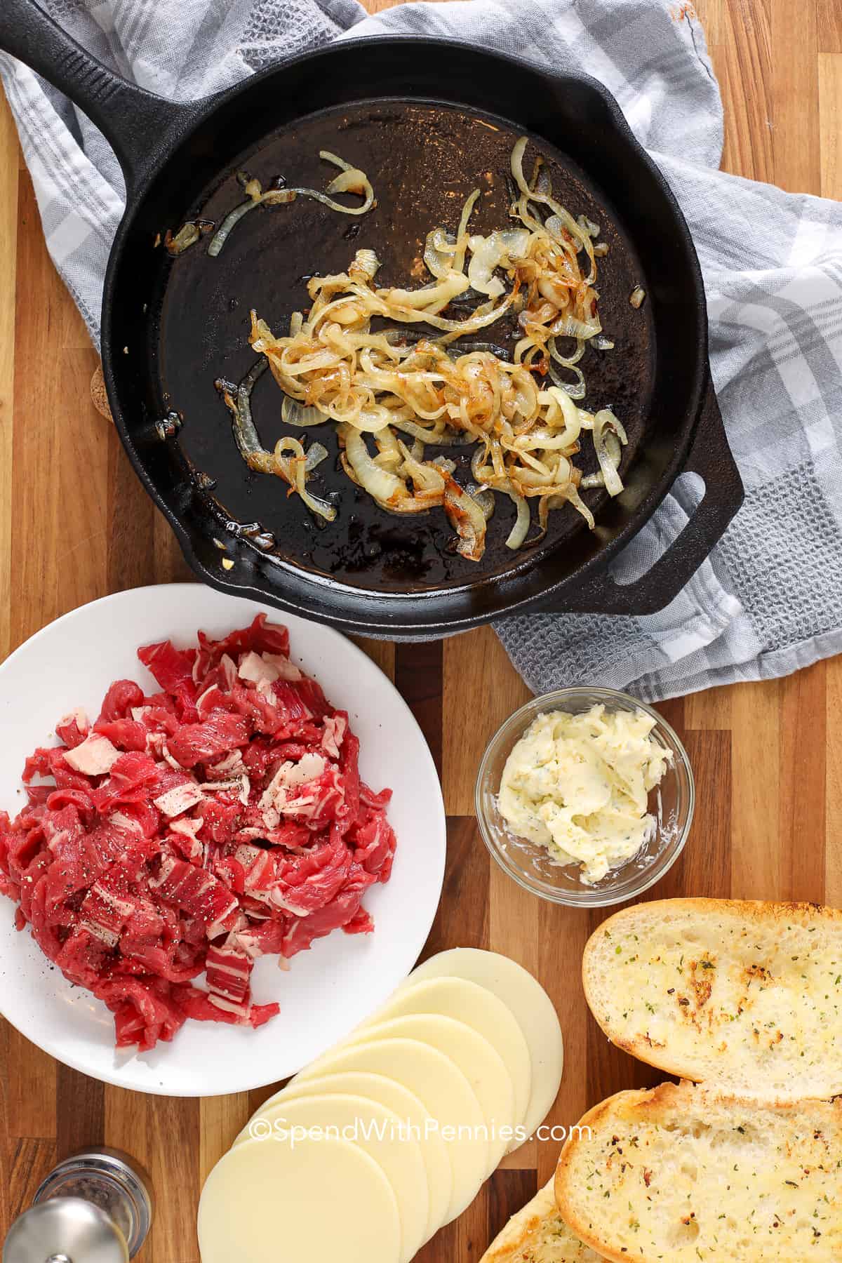 Ingredients for for cheesesteaks on a wood board