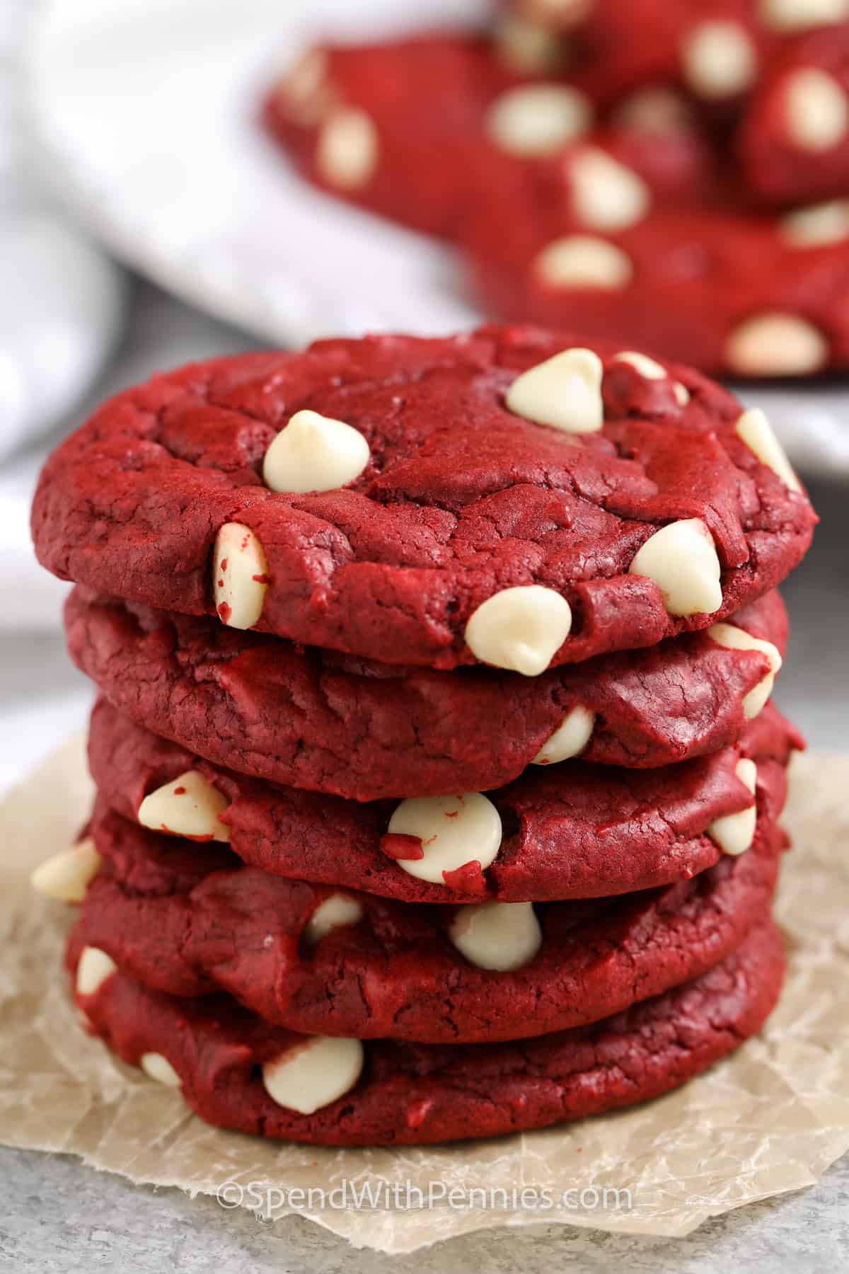 stack of Red Velvet Cake Mix Cookies with a plate full in the back