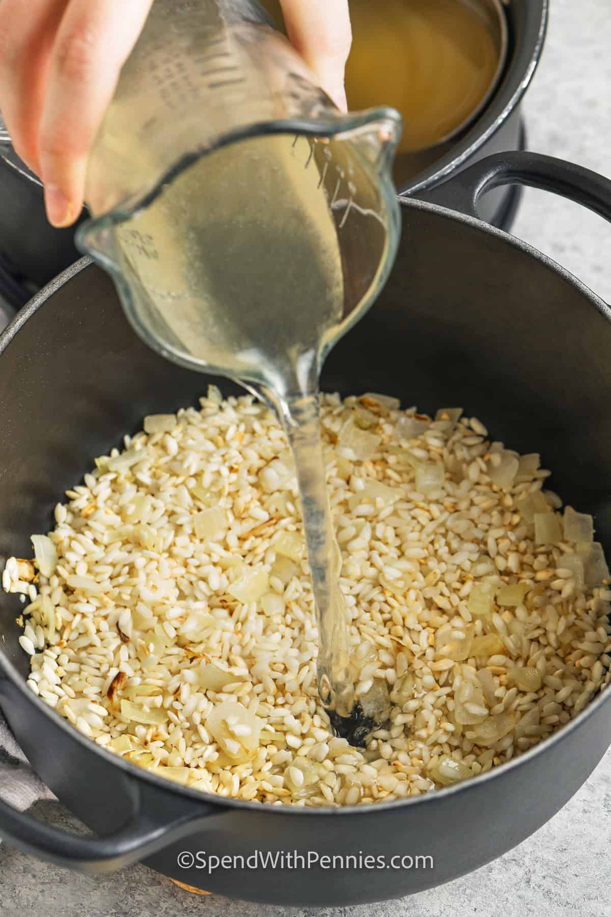 adding liquid to rice and onion in pot to make Shrimp Risotto