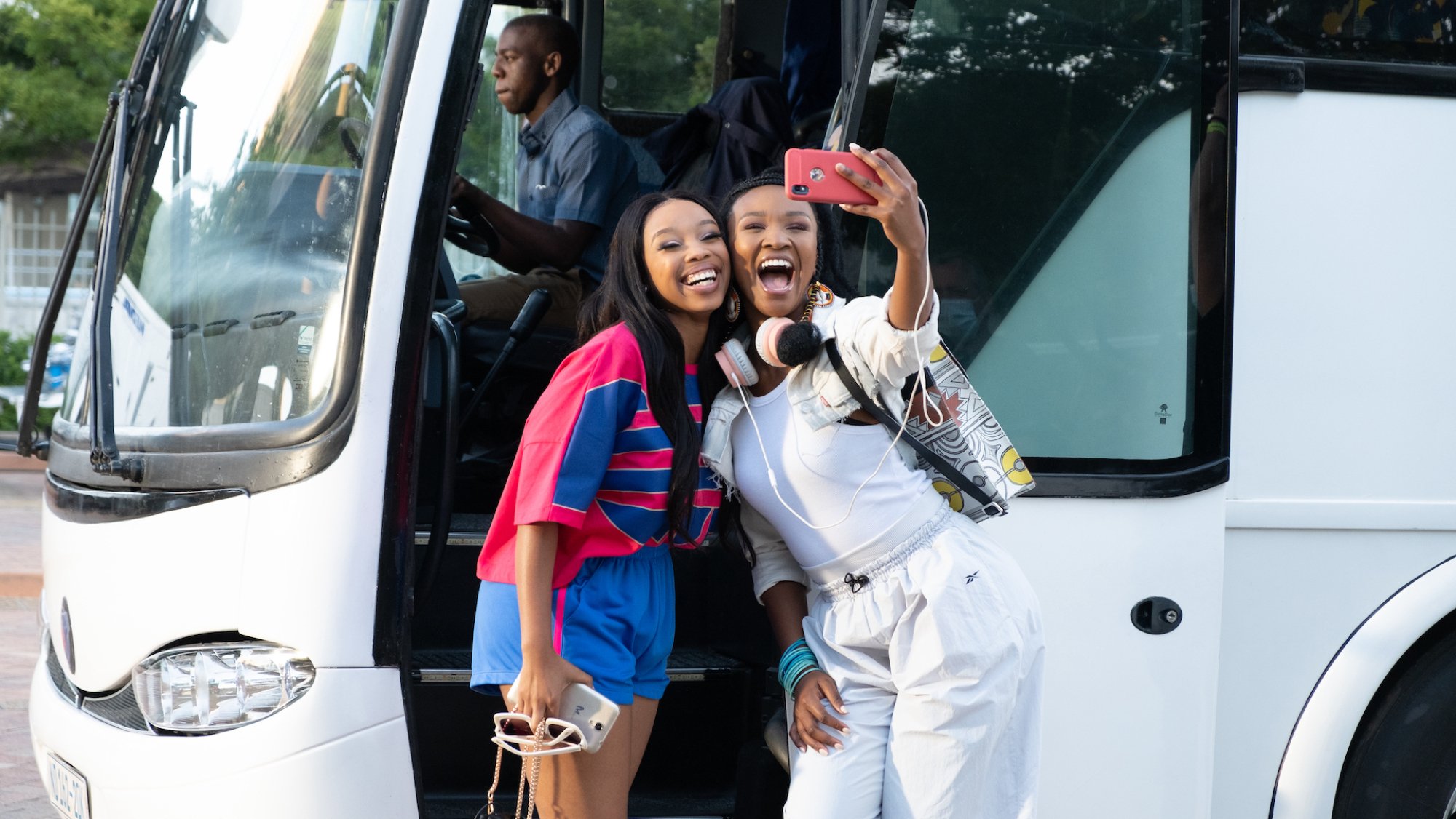 Two women pose for a selfie in front of a coach.