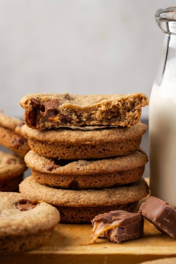 Close up of a stack of extra-thick Milky Way cookies next to a jug of milk.