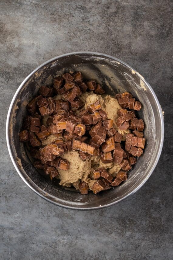 Chopped Milky Way candy bars added to cookie dough in a mixing bowl.